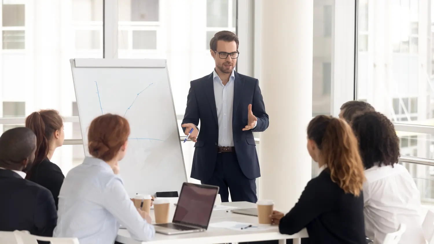 Männlicher Business-Coach-Sprecher im Anzug hält Flipchart-Präsentation